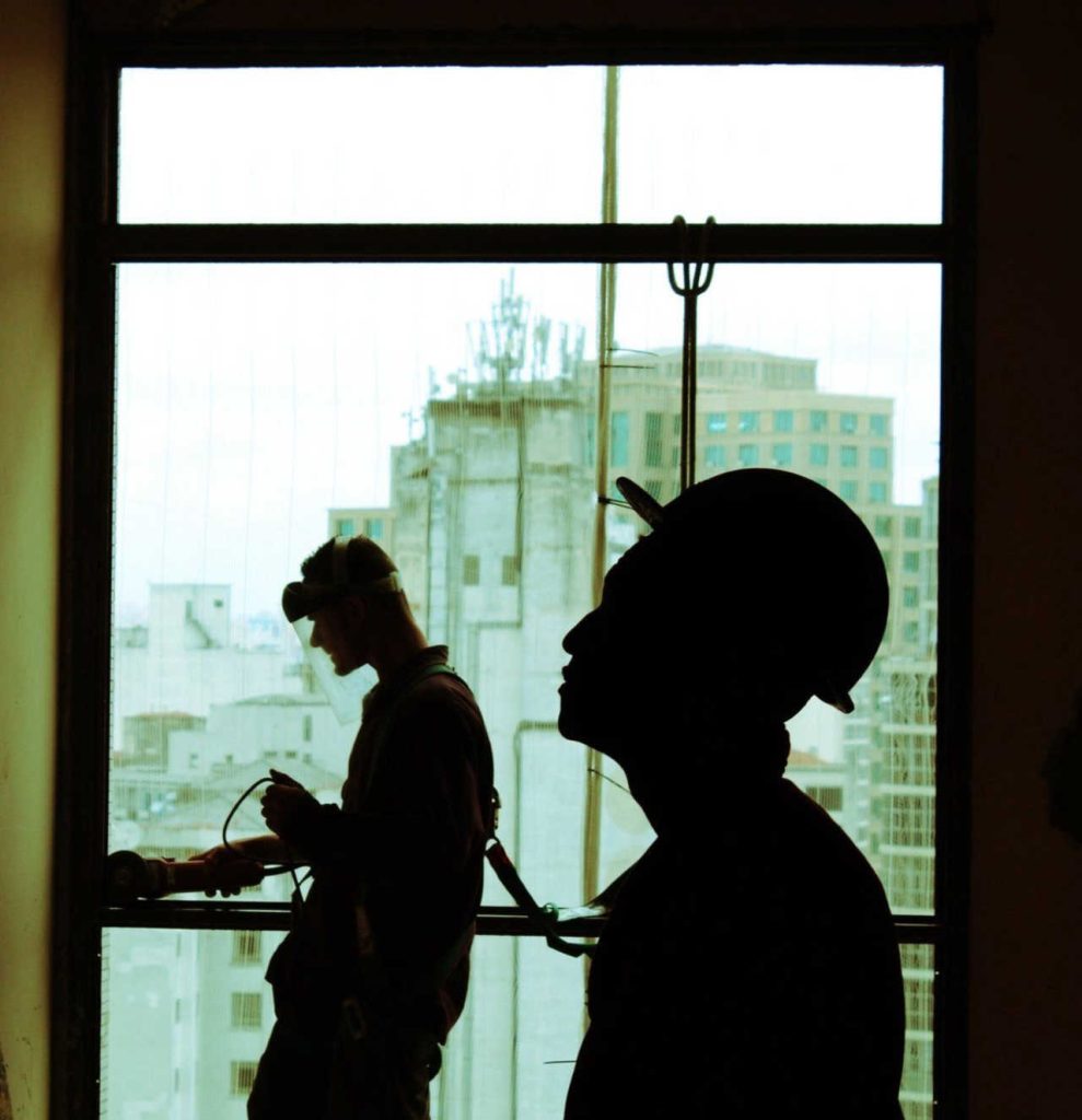 Two people in silhouette by window with urban view outside