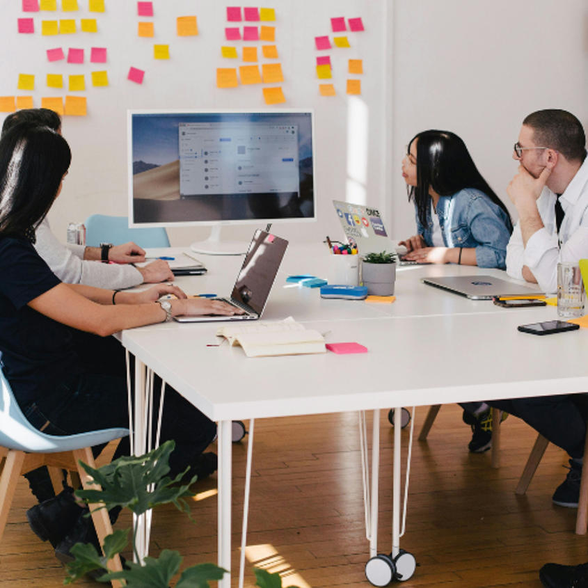 Business team brainstorming with colorful sticky notes on wall and laptop presentation in modern office