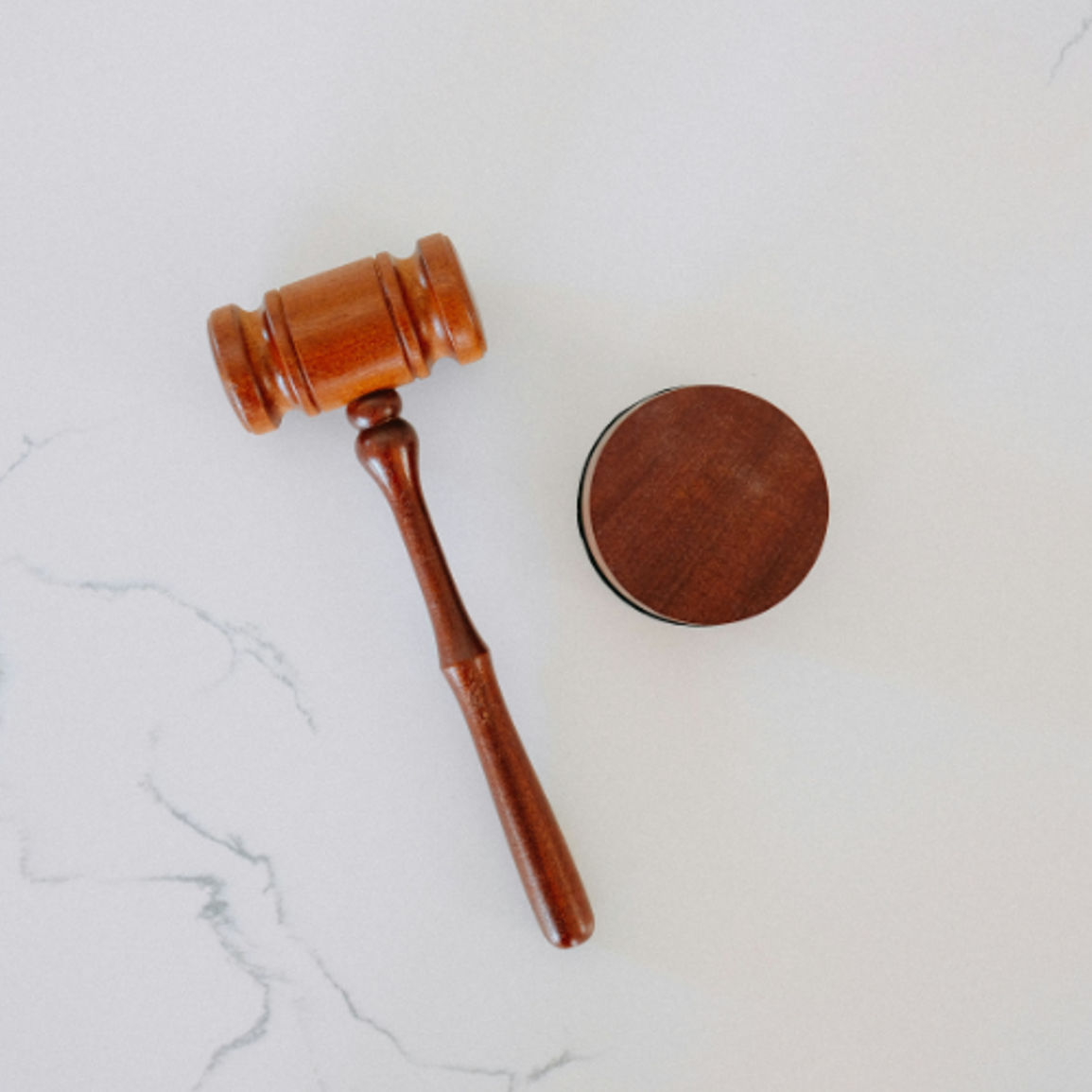 Wooden judge gavel and sound block on white marble surface